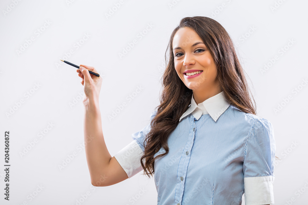 Portrait of beautiful businesswoman pointing with pen on gray background. Portrait of beautiful businesswoman pointing with pen on gray background.