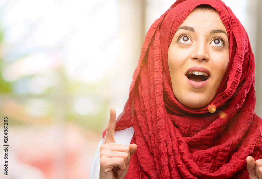 Young arab woman wearing hijab happy and surprised cheering expressing wow gesture pointing up Young arab woman wearing hijab happy and surprised cheering expressing wow gesture pointing up