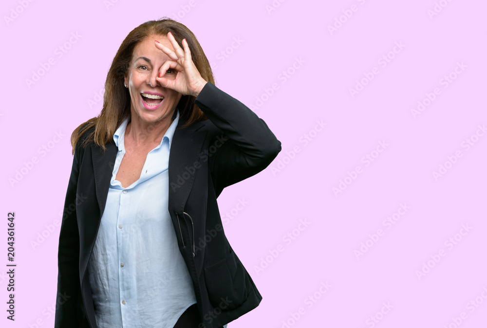 Middle age business woman looking at camera through her fingers in ok gesture. Imitating binoculars, beautiful eyes and smile Middle age business woman looking at camera through her fingers in ok gesture. Imitating binoculars, beautiful eyes and smile