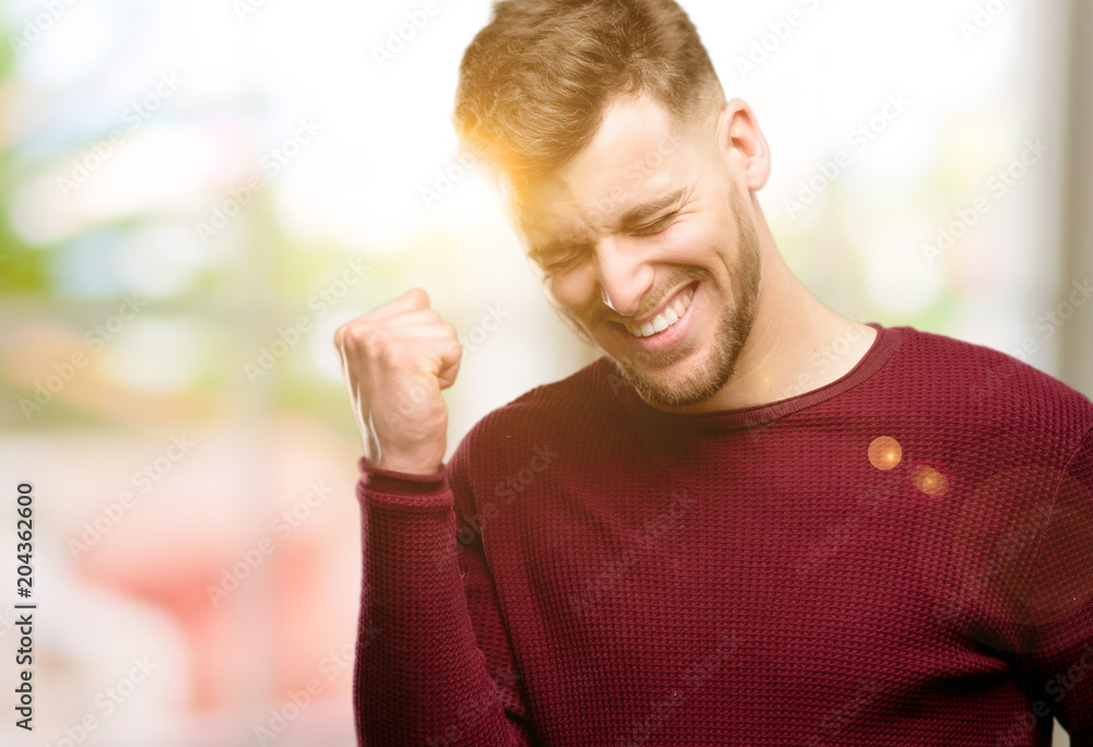 Handsome young man happy and excited celebrating victory expressing big success, power, energy and positive emotions. Celebrates new job joyful Handsome young man happy and excited celebrating victory expressing big success, power, energy and positive emotions. Celebrates new job joyful
