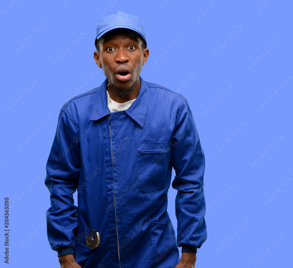 African black plumber man scared in shock, expressing panic and fear African black plumber man scared in shock, expressing panic and fear