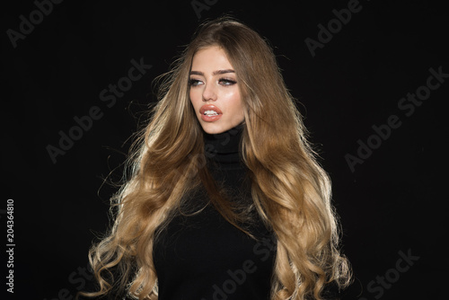 Healthy hair. Beautiful attractive girl with long hair. Sexy woman in black dress with sensual lips, bright makeup, shiny blond hair. Sensual woman with beauty face. Hairstyle, hairdressing concept.