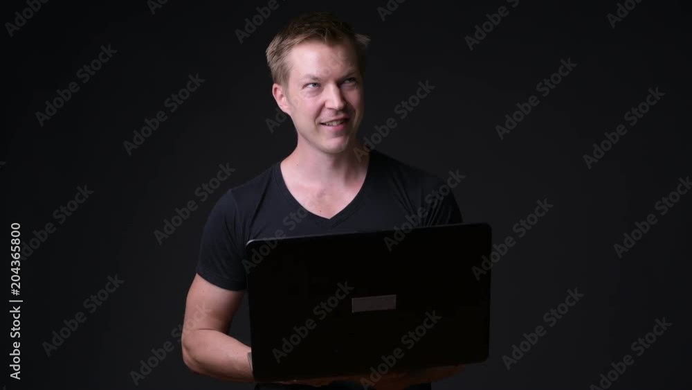 Young handsome man with laptop against black background Young handsome man with laptop against black background