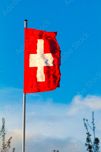 Swiss Confederation, Switzerland national flag waving on blue sky background photo