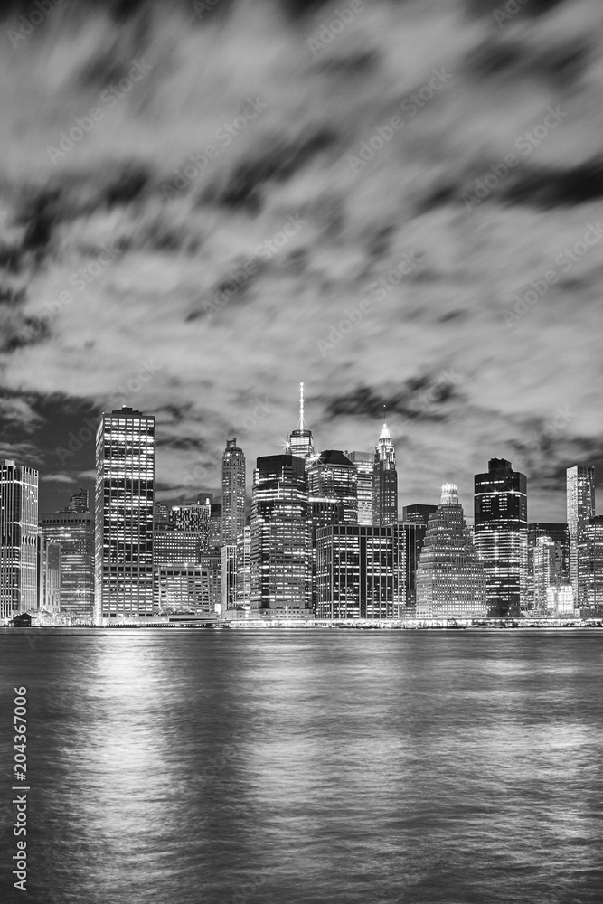 Black and white picture of Manhattan skyline illuminated at night, New York City, USA.