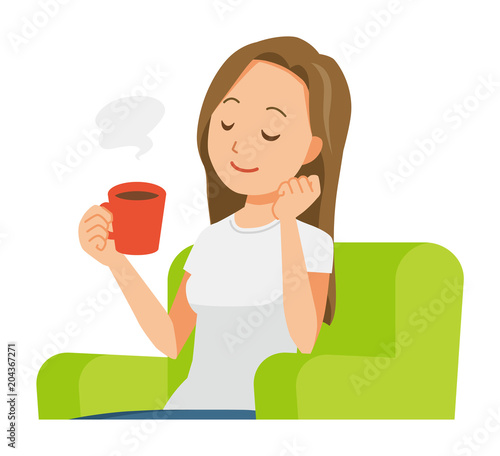 A long hair young woman is sitting on a sofa and drinking coffee