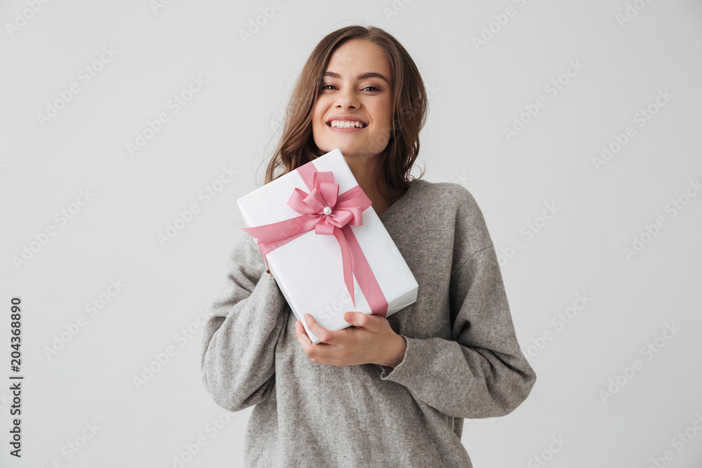 Smiling brunette woman in sweater holding gift box Smiling brunette woman in sweater holding gift box