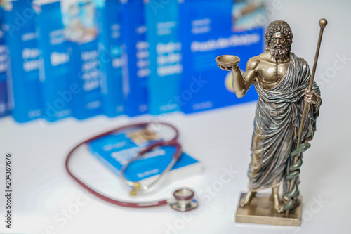 Hippocrates statue on blured medical books and stethoscope background photo