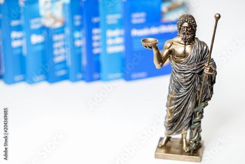 Photos Hippocrates statue on blured medical books and stethoscope background