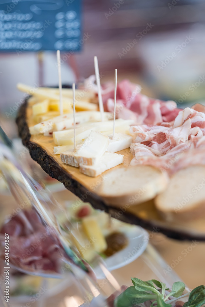 Delicious snack platter with cheese and ham on display on the buffet of a restaurant Delicious snack platter with cheese and ham on display on the buffet of a restaurant