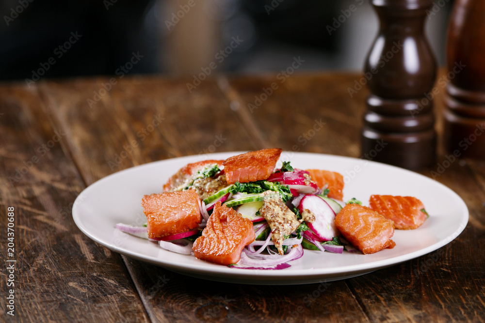 Grilled salmon with radish and spinach, served on white plate. View from above, top studio shot Grilled salmon with radish and spinach, served on white plate. View from above, top studio shot
