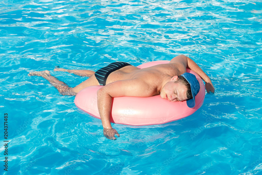 drunk resting guy on the inflatable circle in the swimming pool of the hotel