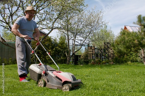 man mowing grass on a garden plot