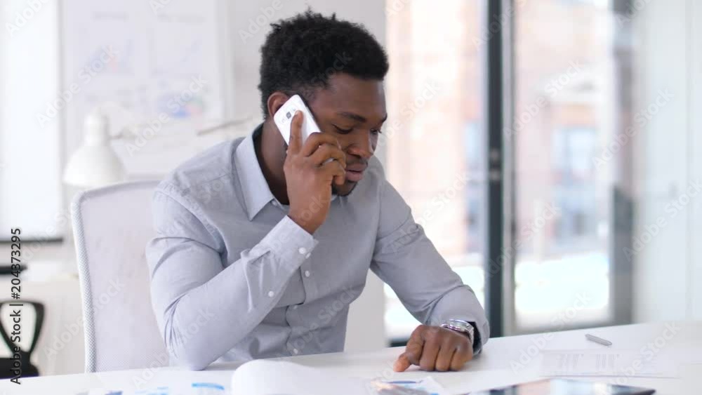 business, technology and communication concept - african american businessman calling on smartphone at office business, technology and communication concept - african american businessman calling on smartphone at office