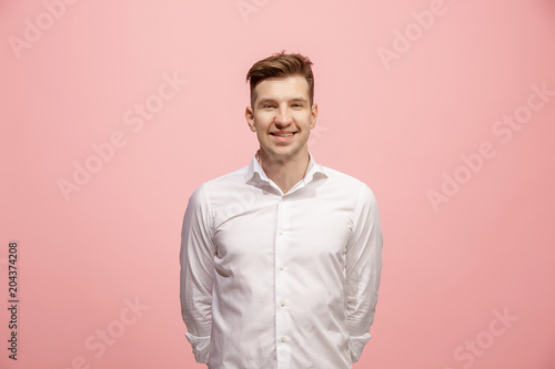 The happy business man standing and smiling against pink background.