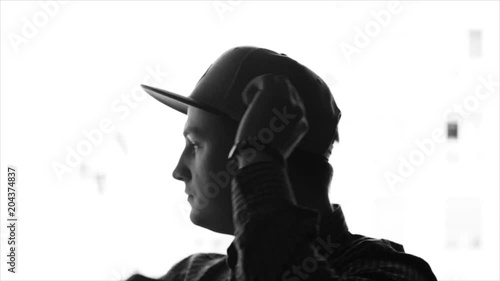Monochrome picture of a young man putting on baseball cap and then looking out the window. Slow motion, sketch, isolated.