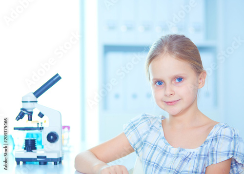 Schoolgirl looking through microscope in science class.
