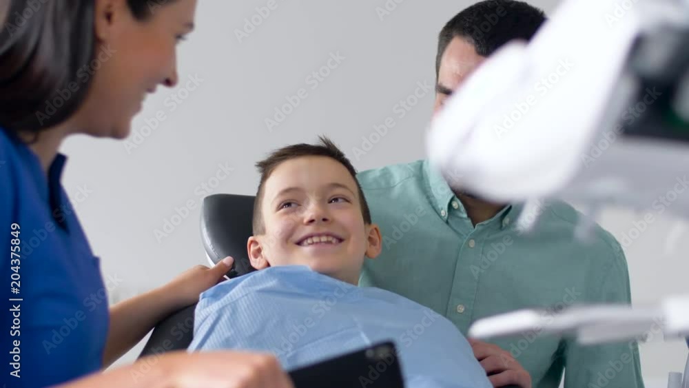 medicine, dentistry and healthcare concept - father and son visiting dentist at dental clinic medicine, dentistry and healthcare concept - father and son visiting dentist at dental clinic