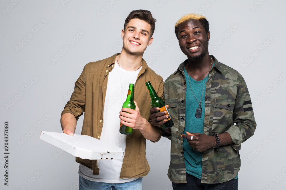 Portrait of a two happy mixed race young men drinking beer and eating pizza while standing isolated over white background Portrait of a two happy mixed race young men drinking beer and eating pizza while standing isolated over white background
