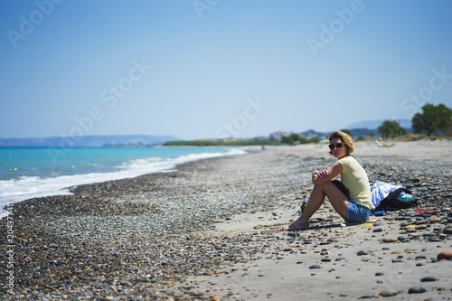 Beautiful girl on the beach watching the sea waves and surf. 