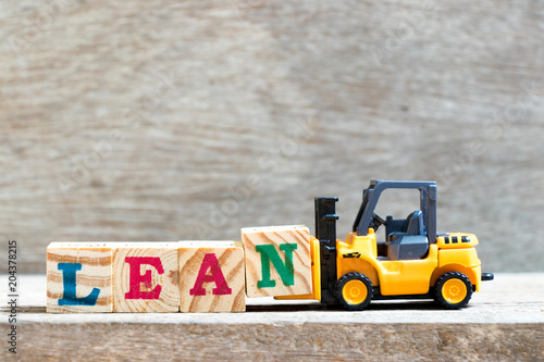 Canvas Print Toy forklift hold letter block n to complete word lean on wood background