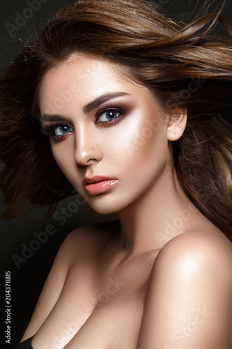 Beautiful woman portrait with windy hair, glamour evening make up and tanned skin.