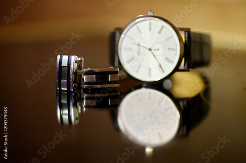 Wristwatches and men's cufflinks lie on the surface of the table.