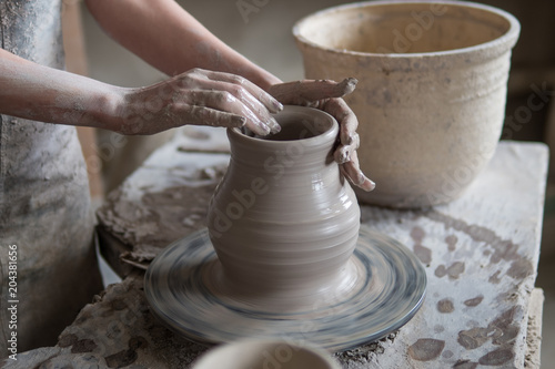 potter sculpts a vase on a potter's wheel © filin174
