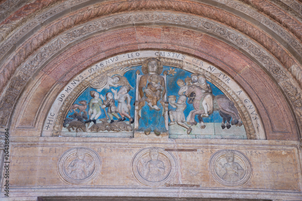 The beautiful portal is surmounted by a lunette in which you can see a polychrome bas-relief depicting the Madonna enthroned with the Child, surrounded by the Magi and the shepherds.