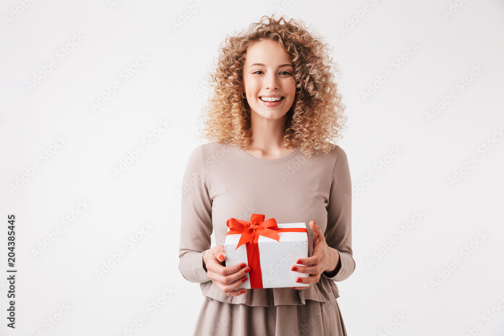 Fototapeta premium Portrait of a cheerful young curly blonde girl in dress
