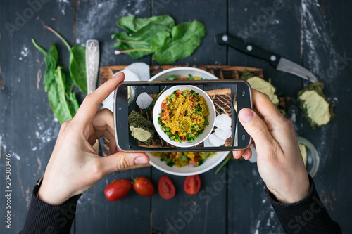 Phone photography of food. Woman hands take photo of lunch with smartphone for social media. Quinoa salad. Raw vegan vegetarian healthy dinner 