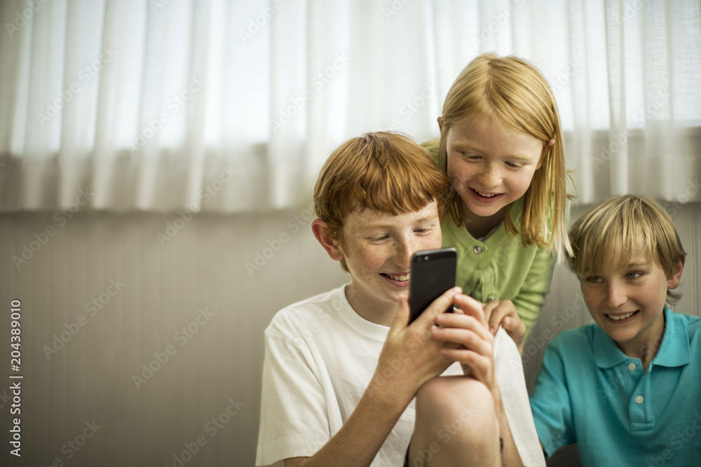 Smiling young siblings playing with a smart phone. Smiling young siblings playing with a smart phone.