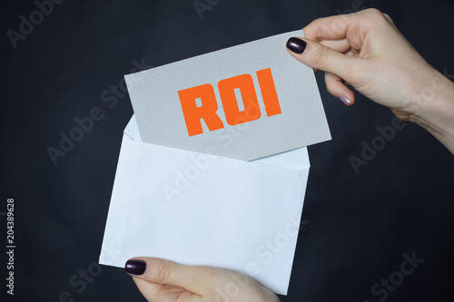 In the hands of a businessman an envelope with the inscription:ROI