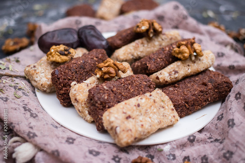 Woman hands holding homemade granola energy bars with dates  coconut  cocoa  walnuts  oats  banana. Healthy sweets diet.Raw vegan vegetarian food.