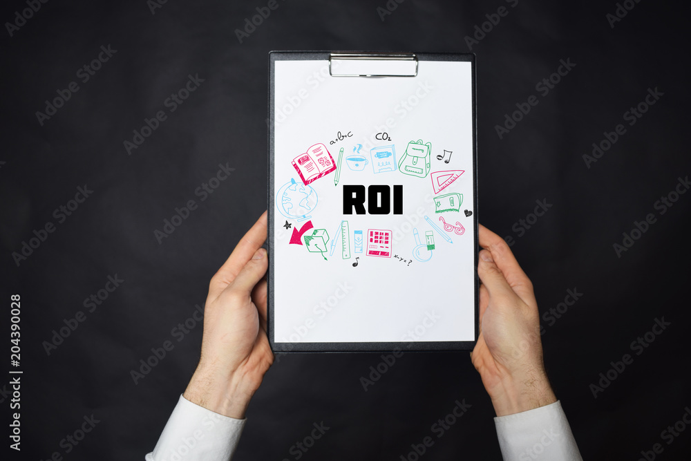 In the hands of a businessman a notebook with the inscription:ROI In the hands of a businessman a notebook with the inscription:ROI