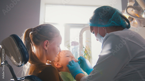Little girl on reception at the dentist, the stomatologist cleaning and watering the child's teeth, girl smiling photo