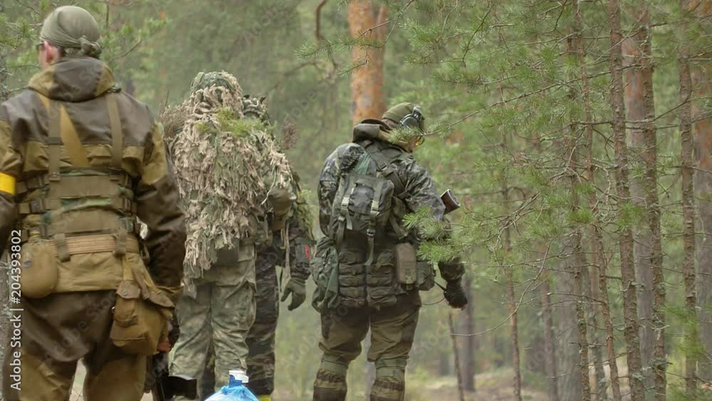 Soldiers in camouflage with combat weapons make their way outside the forest, with the aim of capturing it, the military concept Soldiers in camouflage with combat weapons make their way outside the forest, with the aim of capturing it, the military concept