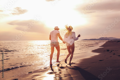 Romantic couple having fun on the beach. Happy couple running on beach at sunset.