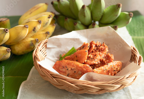 Close up view of fried banana sprinkled with black sesame seeds. Pile on a basket weave.