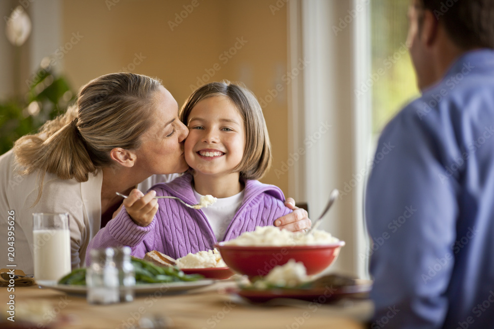 Happy family sharing a meal together around a dining table. Happy family sharing a meal together around a dining table.