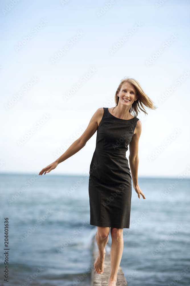 Happy businesswoman walking by the sea with arms outstretched. Happy businesswoman walking by the sea with arms outstretched.