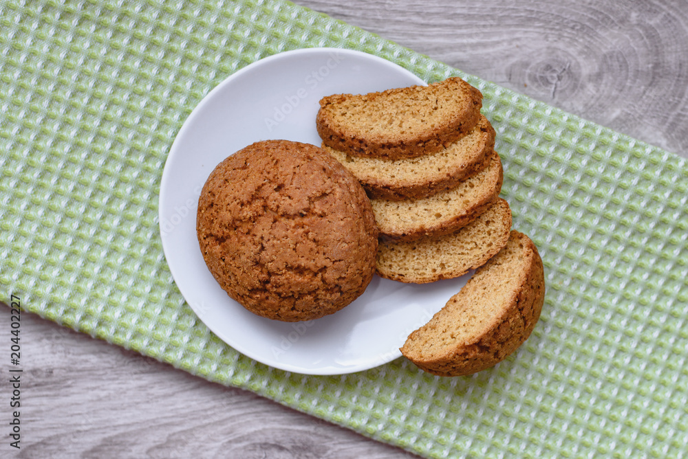 Homemade cookies on a white saucer and green napkins on a wooden background