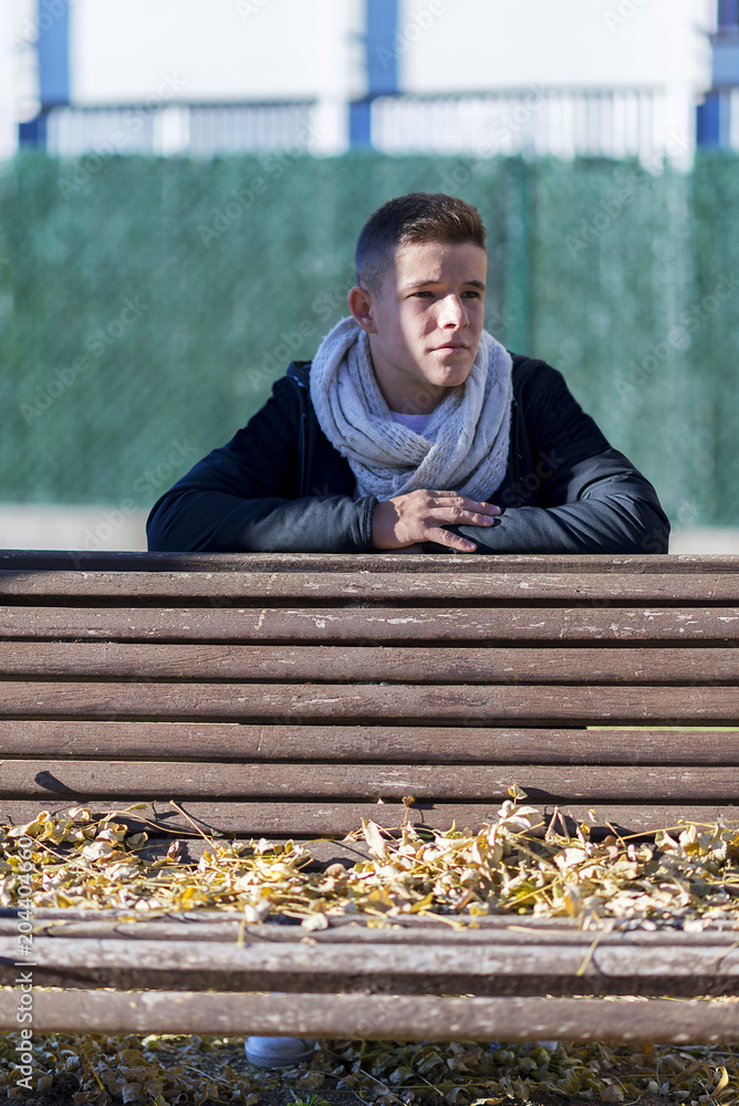 Fototapeta premium Teenager man in relax posture in garden wooden bench