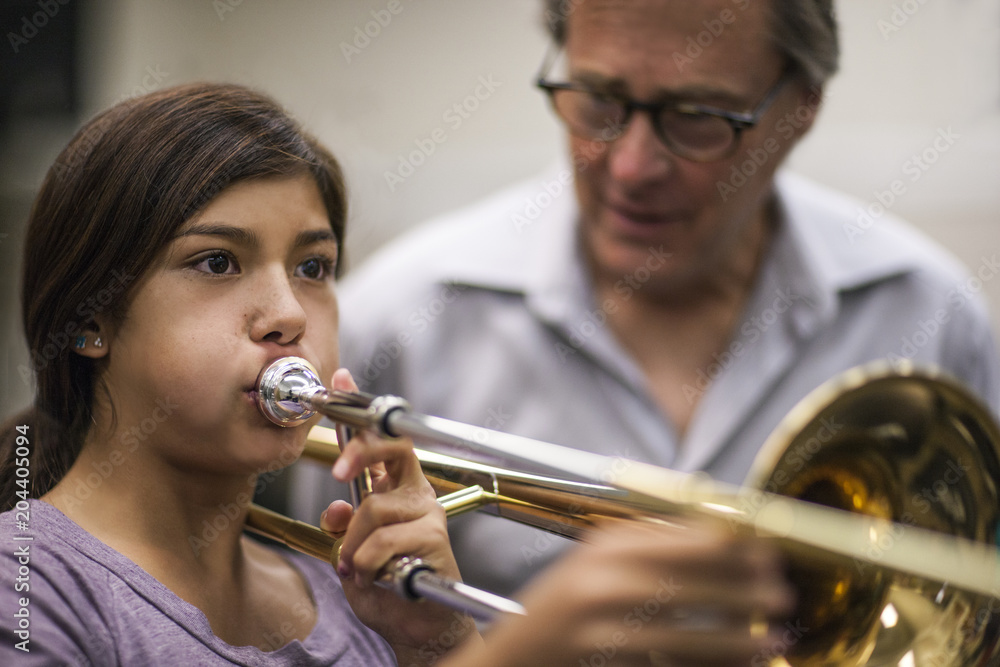 Teenage girl learning to play trombone at music class