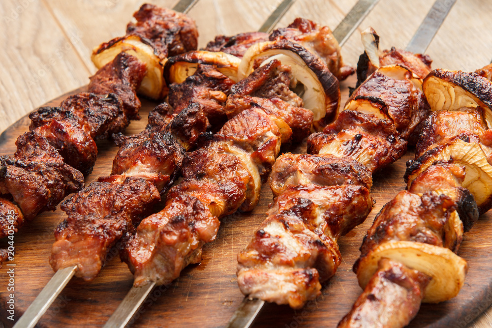 Grilled pork on skewers roasted on the grill on wooden chopping board