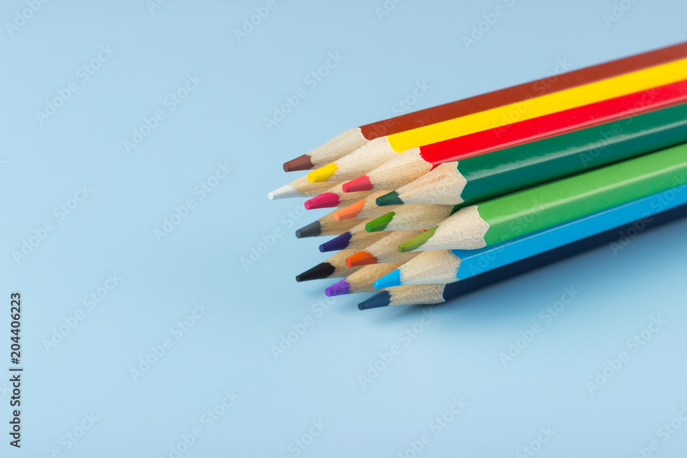 Naklejka premium A bunch of colored pencils lying on a blue background.