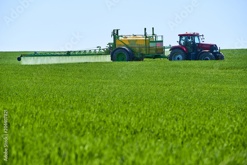  Tractor spraying wheat field with sprayer 