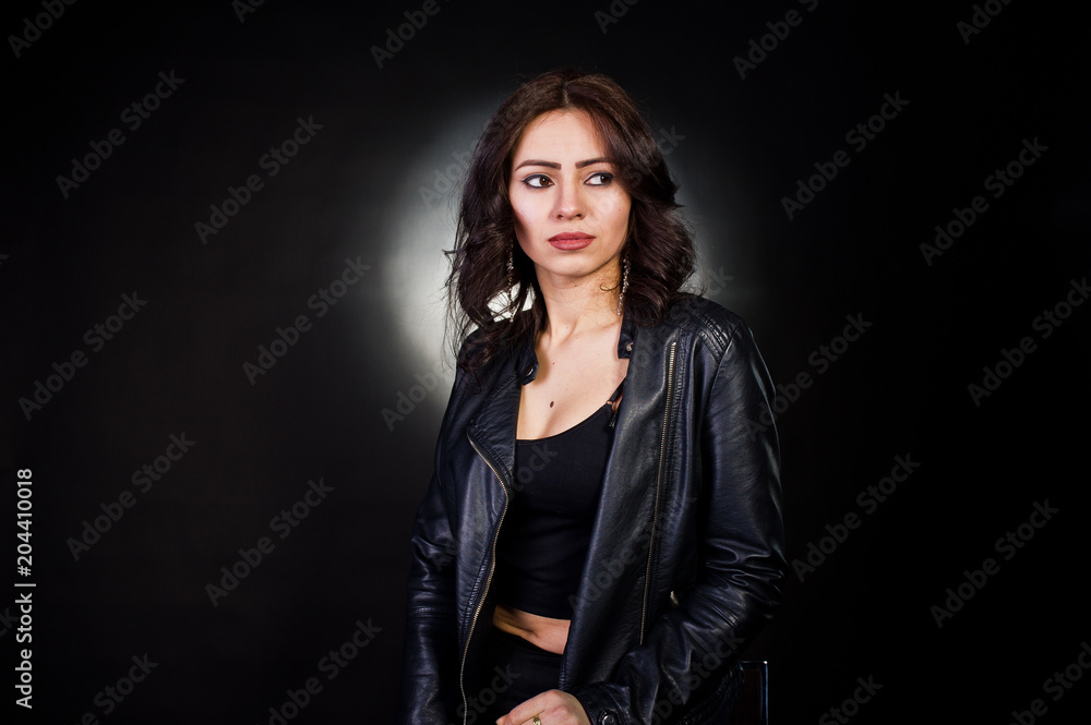 Studio portrait of sexy brunette girl in black leather jacket against black background. Studio portrait of sexy brunette girl in black leather jacket against black background.