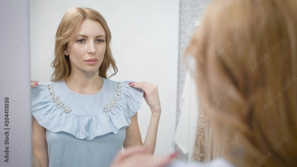 Close up shot of a charming woman trying on a new blue dress. Close up shot of a charming woman trying on a new blue dress.