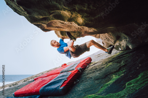 Young climber man climbing at the coast